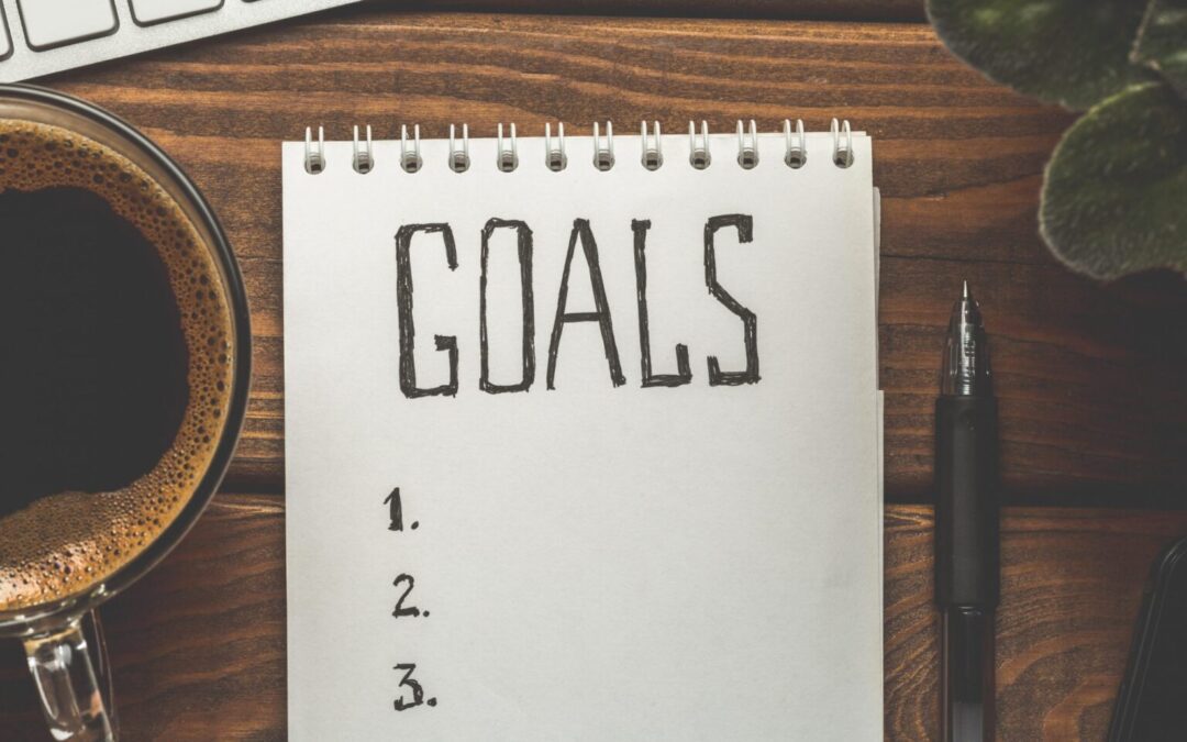 a notebook with the word goals on it next to a cup of coffee
