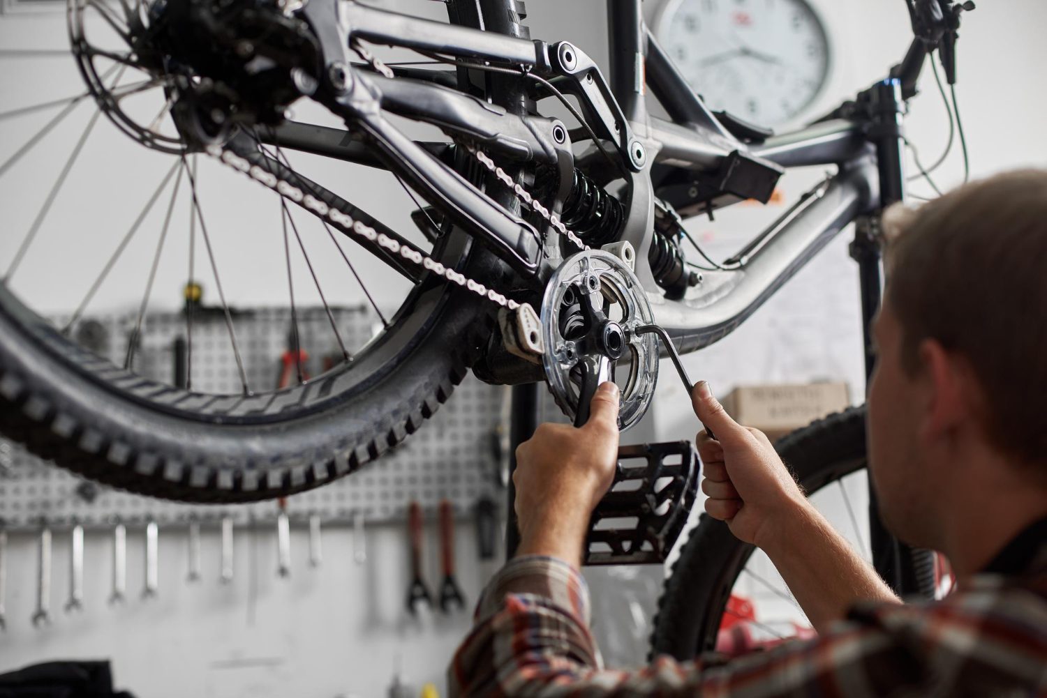 Male mechanic making service in bicycle repair shop using tools